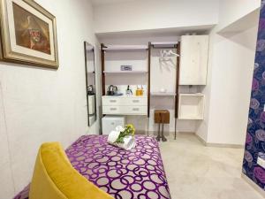 a small room with a purple bed and a kitchen at Cà De La Corona EXPERIENCE in Chioggia