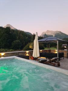 a swimming pool with an umbrella and a table and chairs at Wellness Chalet Apartment Hochkalter in Bischofswiesen