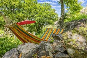 a hammock with a red umbrella next to some rocks at Casa Di Babbo in Olmi-Cappella