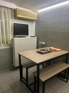 a table and bench in a room with a tv at Antonioy Apartment Kalampaka in Kalabaka