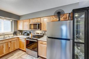 a kitchen with wooden cabinets and a stainless steel refrigerator at Easily Explore Anchorage! Modern Duplex Near Town in Alaska Regional Hospital Heliport