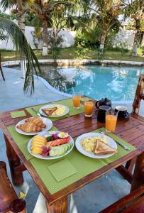 a wooden table with plates of food on it next to a pool at Green Oasis in Nungwi