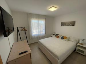 a small bedroom with a bed and a television at Apartamento Terraza Mar in Malgrat de Mar
