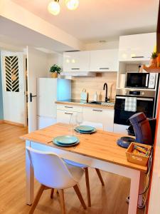 a kitchen with a wooden table with two chairs at Le Beau Dolois - Appartement Climatisé au Coeur de DOLE avec Parking GRATUIT à proximité in Dole
