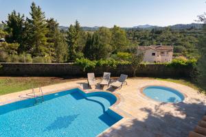 a swimming pool with chairs and a house in the background at Villa Olympic Azure with Private Pool in Dassia