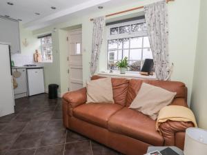 a brown leather couch in a living room with a window at Figgy Cottage in Ripon