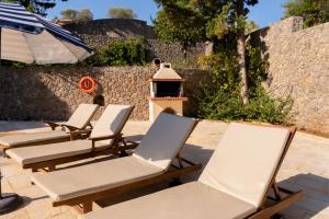 four lounge chairs and an umbrella on a patio at Villa Olympic Azure with Private Pool in Dassia
