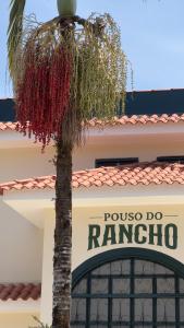 a palm tree in front of a building with a sign at Pouso do Rancho in São José do Barreiro