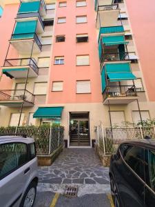 a tall pink building with cars parked in front of it at La Casa di Riki by PortofinoVacanze in Rapallo