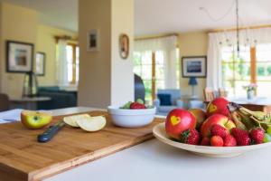 a table with a bowl of fruit on a cutting board at Das Sonnenhaus in Lindaunis +18 photos