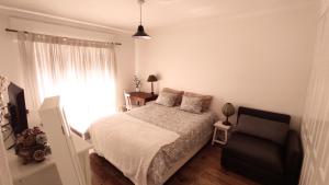 a bedroom with a bed and a chair and a window at DockApartment in Vila Nova de Gaia