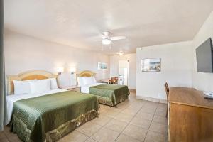 a hotel room with two beds and a flat screen tv at La Terrace Oceanfront in Hollywood