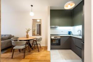 a kitchen with black cabinets and a table and chairs at Fratello Apartment in Podgorica