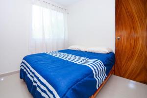 a bedroom with a bed with a blue blanket and a window at Newly renovated apartment with pool in Santa Cruz Huatulco