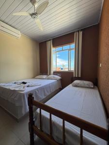 two beds in a room with a window at Pousada Fênix,com piscina -250 METROS DA PRAIA in Pontal do Paraná +86 photos