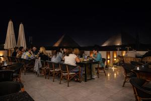 a group of people sitting at tables in a restaurant at Pyramids Holiday Escape in Cairo