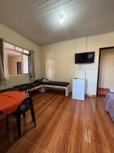 a living room with a couch and a tv on the wall at Pousada Fênix,com piscina -250 METROS DA PRAIA in Pontal do Paraná