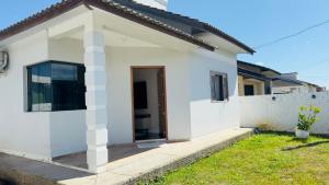 a white house with a door and a yard at Jardim dos Ipês in Araranguá
