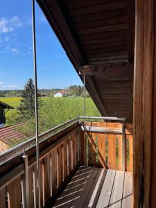 a wooden balcony with a view of a field at Charmantes Dorf-Apartment in Dietramszell