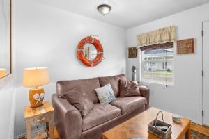 a living room with a brown couch and a table at Easy Street Cottage in Rockaway Beach