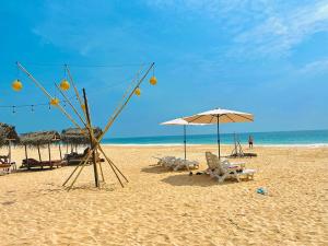 a beach with chairs and an umbrella and the ocean at Villa Jesmin Home - Sea View in Habaraduwa Central +1 photo