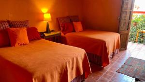 a bedroom with two beds with orange sheets at Posada de la cruz #4 in Querétaro