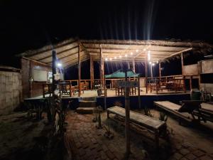 a wooden building with tables and chairs at night at Mancora Beach House in Máncora +49 photos