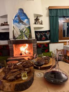 a table with glasses of wine and a fireplace at AETIA -TSIOURGIAKA MPATSILAS Group in Aetia