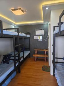 a room with three bunk beds and a table at Aloha Aina Dive Resort in Mabini