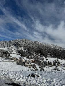 a snow covered hill with houses on a mountain at AETIA -TSIOURGIAKA MPATSILAS Group in Aetia