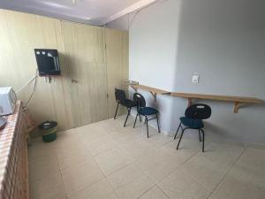 a room with chairs and a table and a tv at Hotel Universo in Goiânia