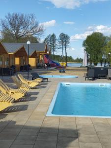 a swimming pool with lounge chairs and a playground at Perła Brenno in Brenno