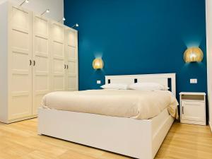 a bedroom with a white bed and a blue wall at Casa Genzino in Molfetta