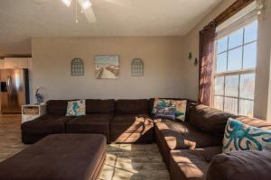 a living room with a brown couch and a large window at Haven Steps to Beach Firepit Pet Paradise in Crystal Beach