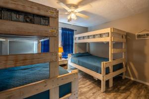 two bunk beds in a room with a ceiling fan at Haven Steps to Beach Firepit Pet Paradise in Crystal Beach