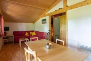 a living room with a table and a red couch at Camping nature 3 étoiles - au coeur des montagnes du Jura in Levier