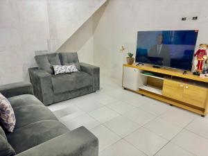 a living room with two chairs and a flat screen tv at Casa com Piscina em Gravatá Carnaval in Gravatá