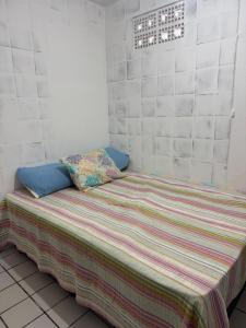 a small bedroom with a bed with a striped blanket at Casa com Piscina em Gravatá Carnaval in Gravatá