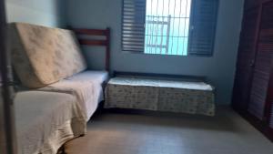 a room with a bed and a bench and two windows at casa azul in Itanhaém +4 photos