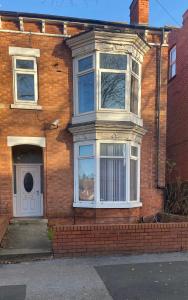 a brick house with a white door and windows at Contractor House with parking in Worksop