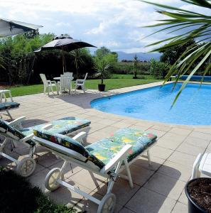 - une piscine avec 2 chaises longues, une table et un parasol dans l'établissement La Clairière, à Guémar
