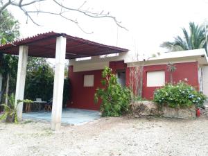 a red house with a porch with a table at Casa Corozo in Bacalar