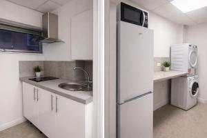 a white kitchen with a sink and a refrigerator at Douglas's House in Dublin