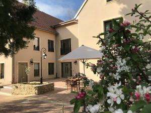a house with a table and an umbrella and flowers at Bel Esprit - Chambres d'hôtes in Kalhausen