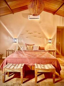 a bedroom with a large bed with two benches at Chalé Caju Knots in Parajuru