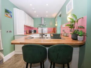 a kitchen with a sink and two green chairs at Tregynrig Bach in Cemaes Bay