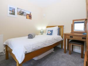 a bedroom with a bed and a desk with a mirror at Tregynrig Bach in Cemaes Bay