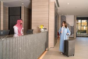 a woman with a suitcase standing in front of a counter at Azha Alriyadh in Riyadh