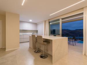a kitchen with a large island with chairs and a large window at Salobre Golf Villas Kaiman in Salobre