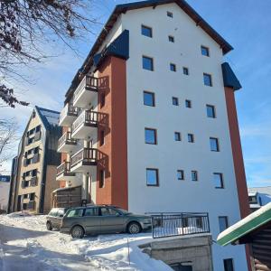 a tall building with a car parked in front of it at Apartman Djurdja in Raška